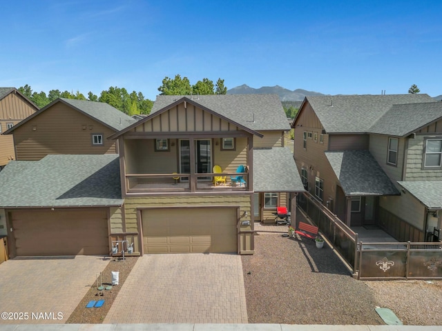 view of front of house featuring decorative driveway, roof with shingles, board and batten siding, and a mountain view