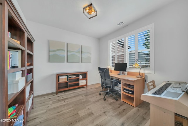 office area with wood finished floors, visible vents, and baseboards