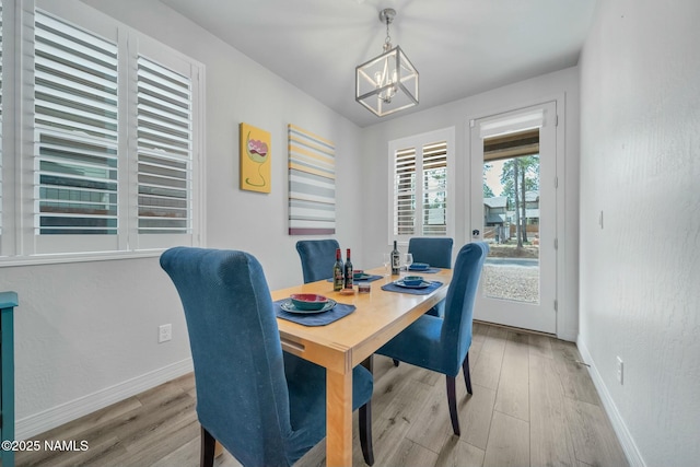 dining area featuring baseboards, an inviting chandelier, and wood finished floors