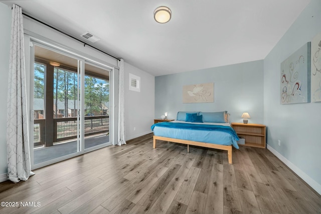 bedroom with visible vents, wood finished floors, baseboards, and access to exterior