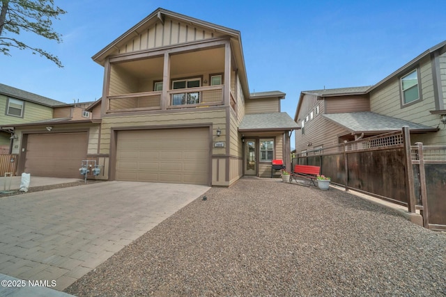 view of front of home featuring board and batten siding, fence, decorative driveway, a balcony, and an attached garage