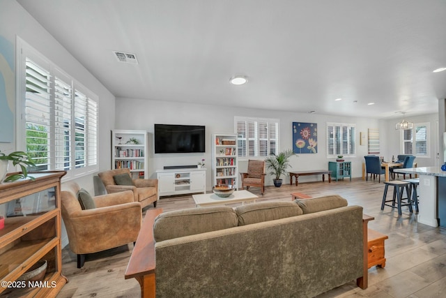 living room featuring recessed lighting, visible vents, an inviting chandelier, and light wood-style flooring