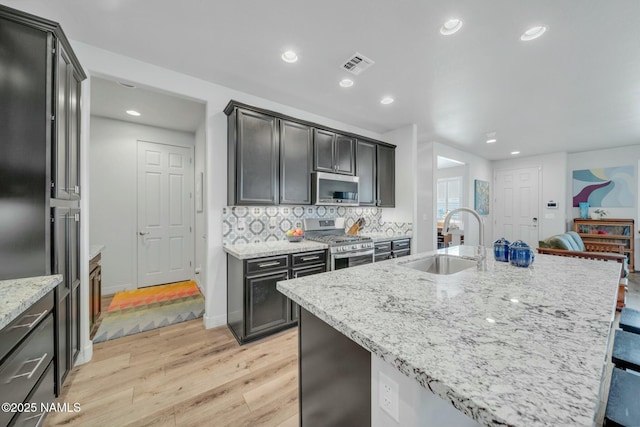 kitchen featuring light stone counters, visible vents, a sink, appliances with stainless steel finishes, and tasteful backsplash