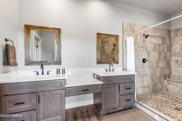 full bath with tiled shower, wood finished floors, and vanity