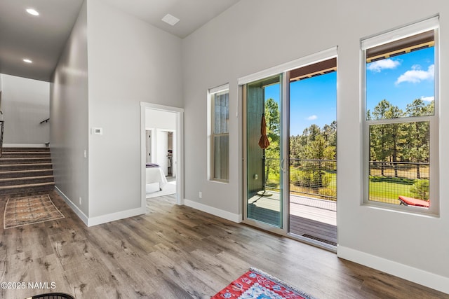 doorway with recessed lighting, stairway, baseboards, and wood finished floors