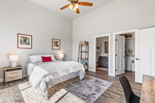 bedroom featuring baseboards, wood finished floors, ensuite bathroom, a spacious closet, and a closet