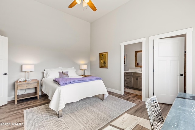 bedroom featuring light wood-style floors, baseboards, vaulted ceiling, and connected bathroom