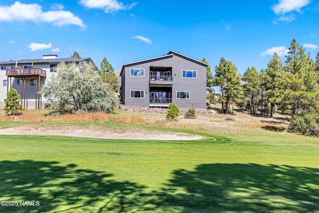 back of property with a lawn and a balcony