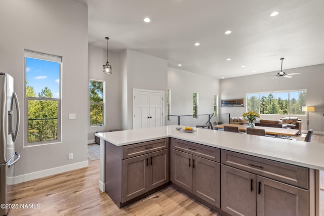 kitchen featuring recessed lighting, open floor plan, light countertops, light wood-type flooring, and stainless steel refrigerator with ice dispenser