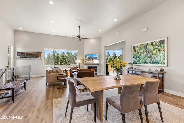 dining room with light wood-type flooring, recessed lighting, baseboards, and a glass covered fireplace