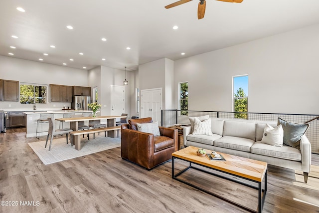 living area featuring light wood-type flooring, a high ceiling, and recessed lighting