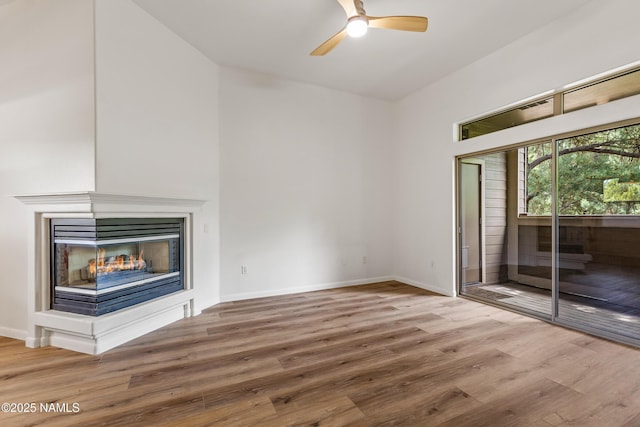 1401 N 4th St Unit 228, Flagstaff, AZ 86004 - unfurnished living room with wood finished floors, a ceiling fan, baseboards, and a multi sided fireplace