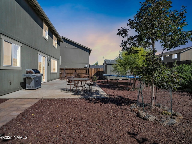 4580 Centaurus Rd, Bellemont, AZ 86015 - yard at dusk featuring a patio area, a fenced backyard, and a trampoline