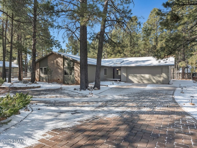 mid-century modern home with a garage, decorative driveway, and brick siding