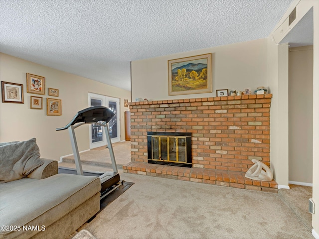 exercise room featuring a textured ceiling, carpet floors, a fireplace, visible vents, and baseboards