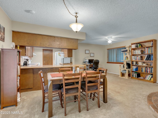 dining room with light carpet, a textured ceiling, and a ceiling fan