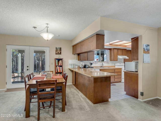 kitchen featuring french doors, light carpet, a sink, white appliances, and a peninsula