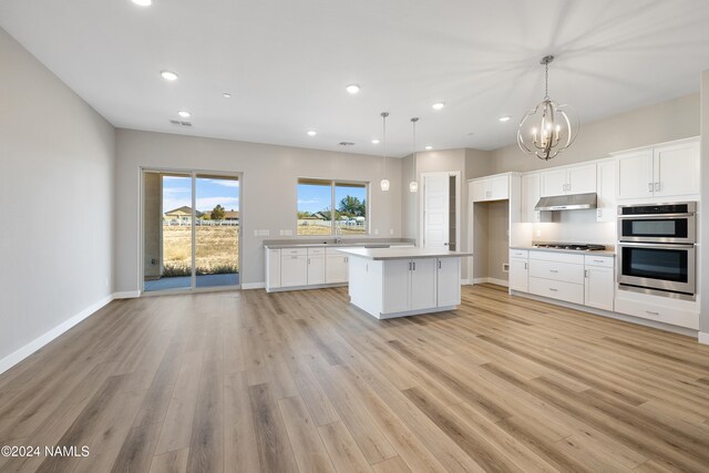 kitchen featuring pendant lighting, appliances with stainless steel finishes, a center island, white cabinetry, and light wood-type flooring