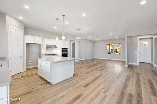 kitchen featuring decorative light fixtures, white cabinetry, light wood-type flooring, and a kitchen island