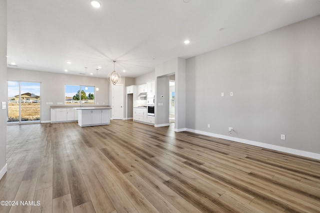 unfurnished living room featuring light hardwood / wood-style floors and a chandelier