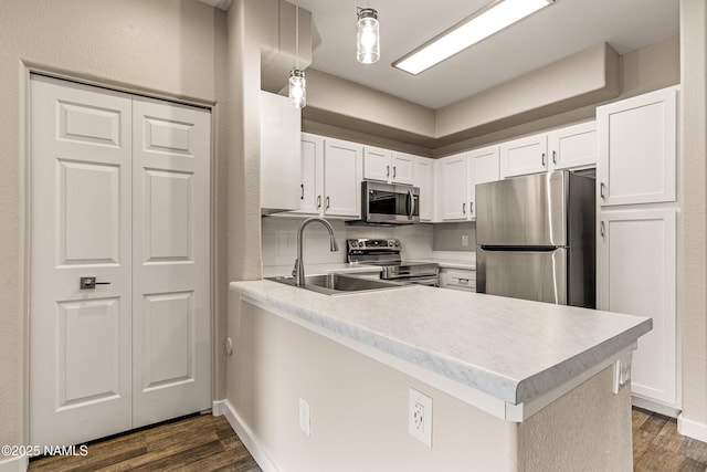 kitchen with decorative light fixtures, kitchen peninsula, white cabinets, and appliances with stainless steel finishes