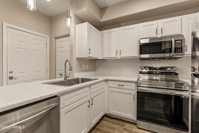 kitchen with sink, white cabinetry, decorative light fixtures, appliances with stainless steel finishes, and decorative backsplash