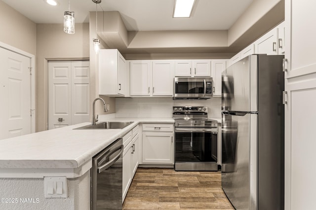 kitchen with sink, appliances with stainless steel finishes, backsplash, white cabinets, and decorative light fixtures