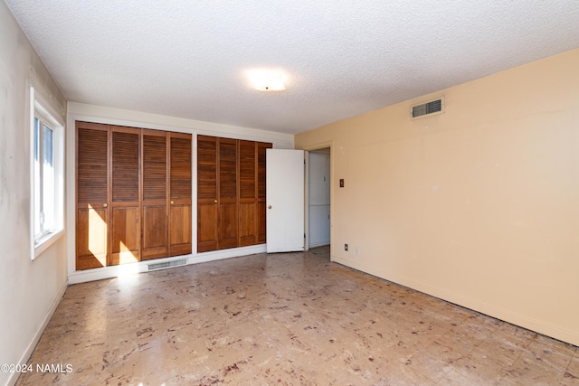 unfurnished bedroom featuring multiple closets and a textured ceiling