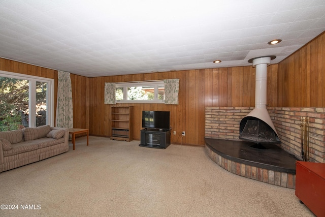 carpeted living room featuring a wood stove and a wealth of natural light