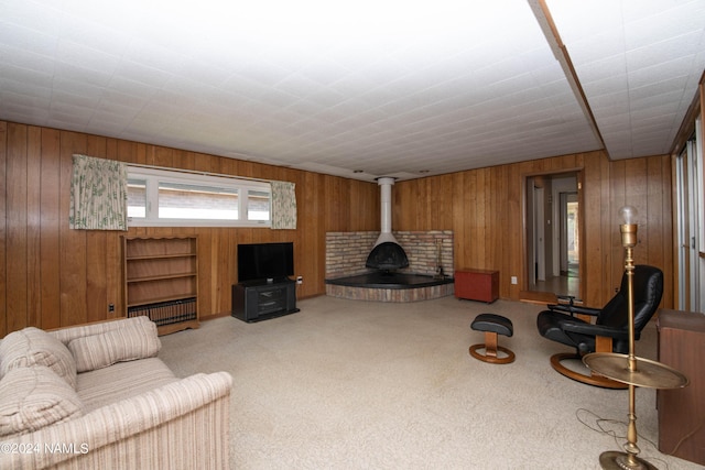 carpeted living room featuring a wood stove and wooden walls