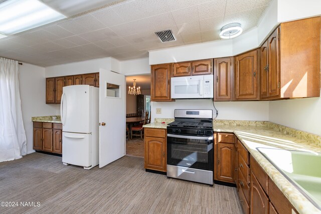 kitchen featuring sink, white appliances, light hardwood / wood-style flooring, and a chandelier