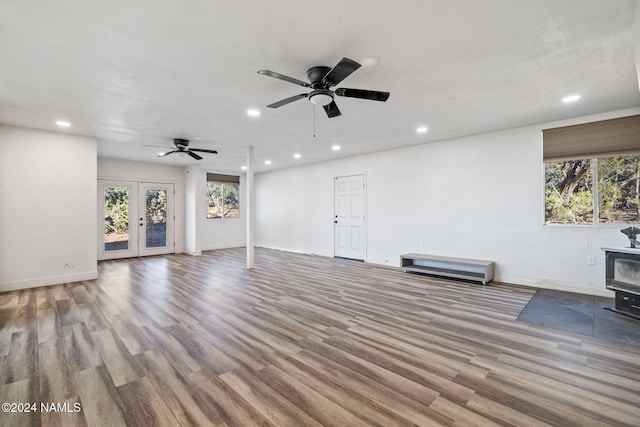 unfurnished living room featuring ceiling fan, light hardwood / wood-style floors, a wood stove, and french doors