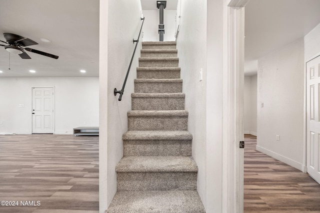 staircase featuring wood-type flooring and ceiling fan