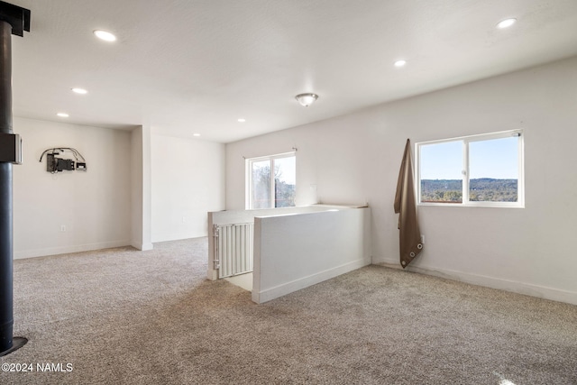 empty room with light colored carpet and a wood stove