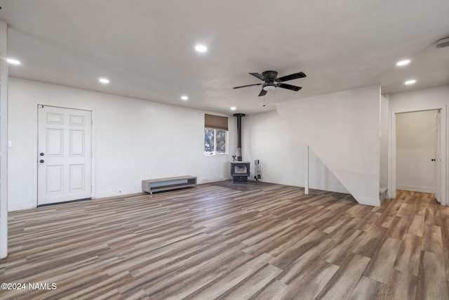 unfurnished living room with ceiling fan, light hardwood / wood-style flooring, and a wood stove