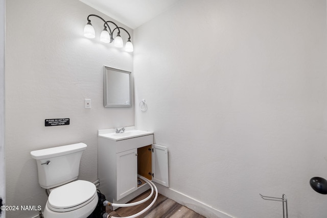 bathroom with hardwood / wood-style flooring, toilet, and vanity