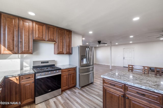 kitchen featuring ceiling fan, light stone counters, light hardwood / wood-style flooring, and appliances with stainless steel finishes