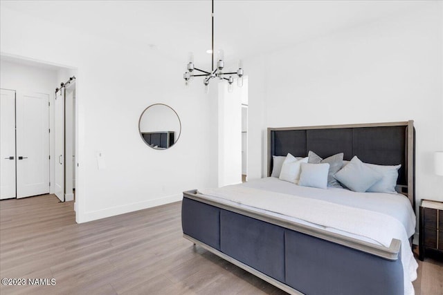 bedroom with wood-type flooring, a chandelier, and a barn door