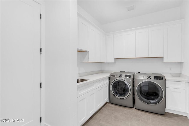 laundry room featuring washer and clothes dryer and cabinets