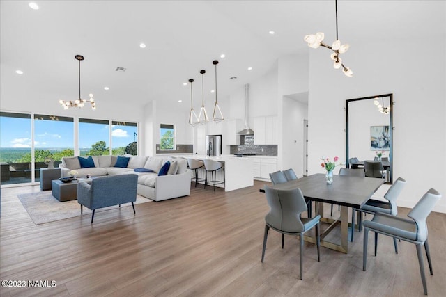 dining room with light hardwood / wood-style floors, a chandelier, a towering ceiling, and a wealth of natural light