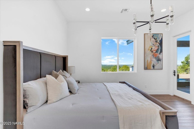 bedroom featuring hardwood / wood-style flooring, access to exterior, and an inviting chandelier