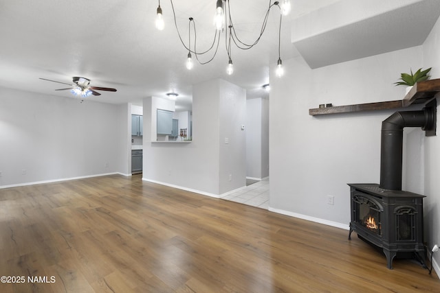 6437 N Conrad Ln, Flagstaff, AZ 86004 - unfurnished living room with a ceiling fan, wood finished floors, a wood stove, baseboards, and a chandelier