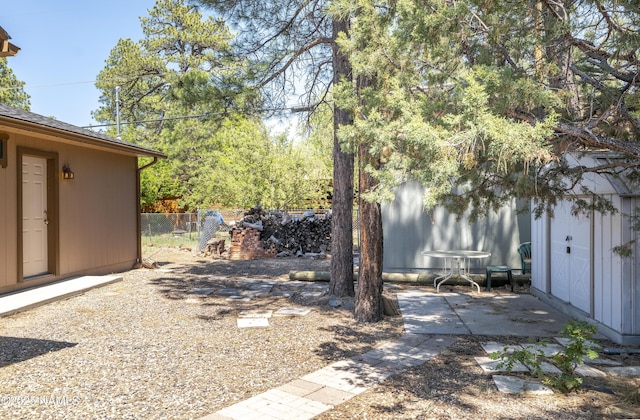 view of yard with an outbuilding, a patio area, fence, and a storage unit