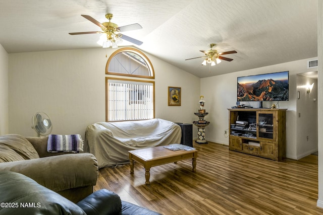 living area featuring a ceiling fan, visible vents, vaulted ceiling, and wood finished floors