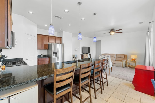 kitchen featuring stainless steel appliances, a peninsula, visible vents, brown cabinets, and pendant lighting