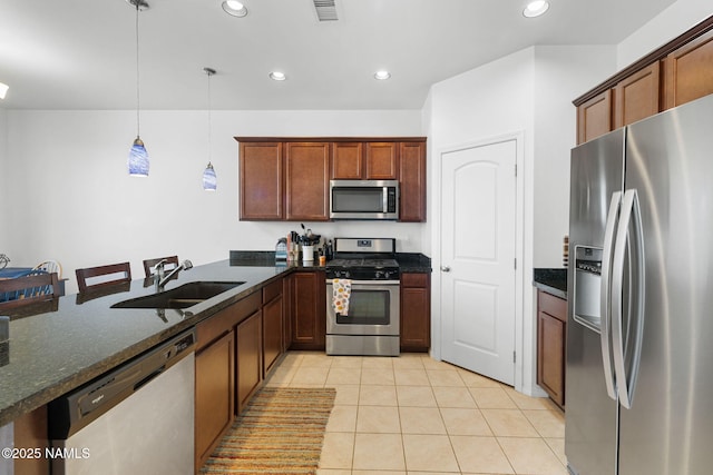 kitchen with light tile patterned floors, visible vents, appliances with stainless steel finishes, dark stone countertops, and a sink