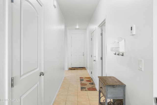 hallway featuring baseboards and light tile patterned flooring