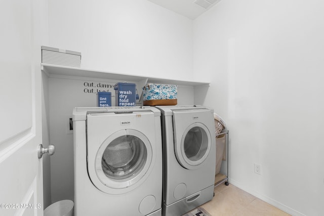 clothes washing area featuring washer and clothes dryer, light tile patterned floors, visible vents, laundry area, and baseboards