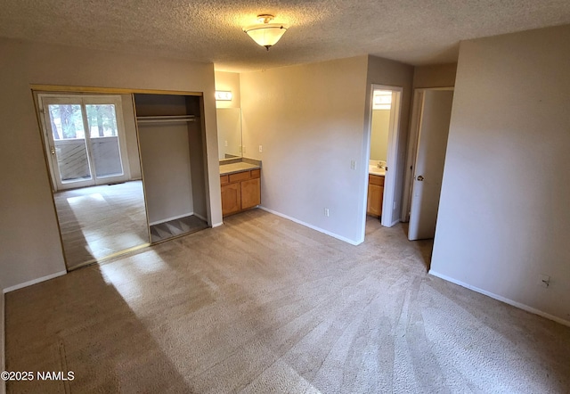 unfurnished bedroom featuring light carpet, baseboards, a textured ceiling, and connected bathroom