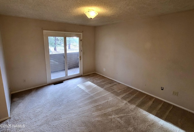 empty room featuring visible vents, a textured ceiling, baseboards, and carpet floors